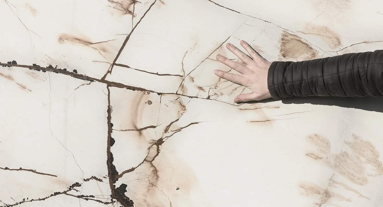 A hand on the freshly opened face of the slab, reading the veining