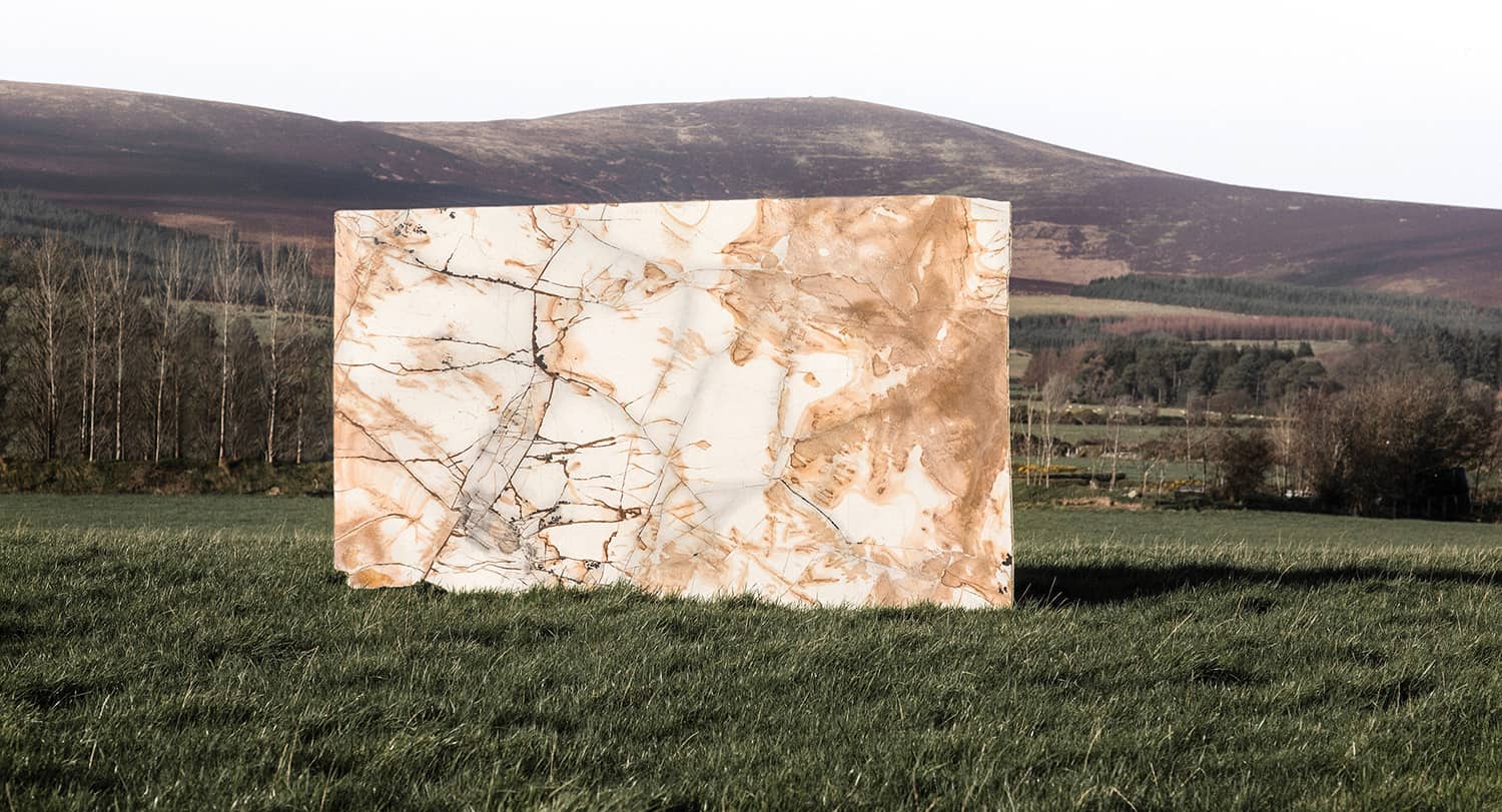 A single slab of natural stone standing in a Wicklow field with the mountains behind it