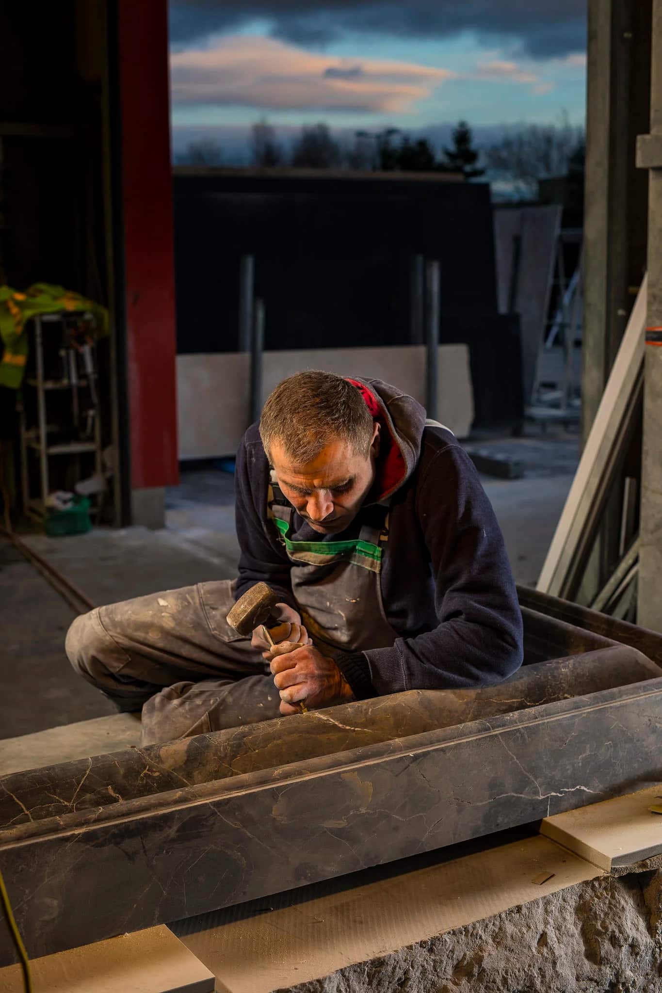 Hands working the profiled edge of a stone slab by hand