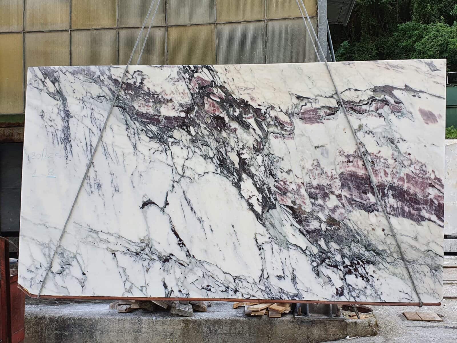 Raw slabs of Calacatta Viola marble leaning against a wall before cutting